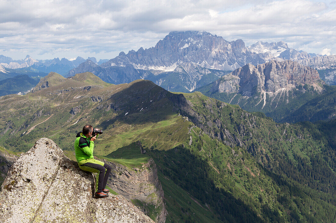 Ein Wanderer beim Fotografieren am Ende des Klettersteigs Via Ferrata delle Trincee, mit dem Berg Civetta im Hintergrund, Padon-Gruppe, Dolomiten, Fassa-Tal, Provinz Trient, Trentino-Südtirol, Italien.