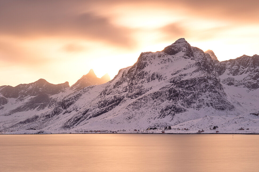 eine Langzeitbelichtung, um das warme Licht während eines Wintersonnenuntergangs am Fredvang Fjord einzufangen, Lofoten, Norwegen, Europa