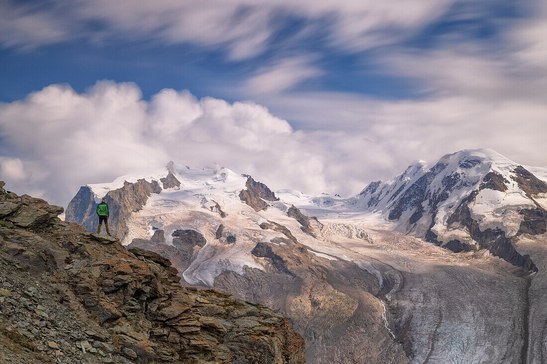 one hiker enjoys the iconic Gornergrat Gletscher and Monte Rosa during an cloudy sunset, Zermatt, Canton of Valais, Switzerland, Europe