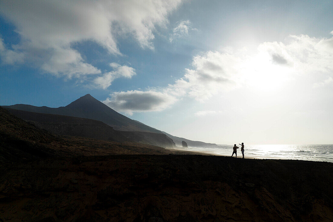 two guys admiring the beautiful landscape near to Cofete beach during a summer day, Natural Park de Jandia, Fuerteventura, Canary Island, Spain, Europe