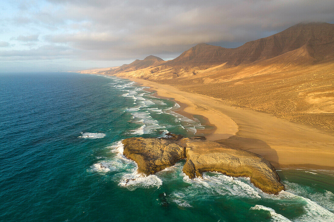 aerial view taken by drone of Cofete Beach during a summer warm sunset with El Isote peninsula in foreground, Natural Park de Jandia, Fuerteventura, Canary Island, Spain, Europe