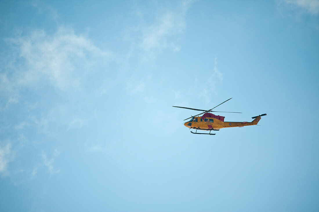 Gelber kanadischer Rettungshubschrauber in blauem Himmel.