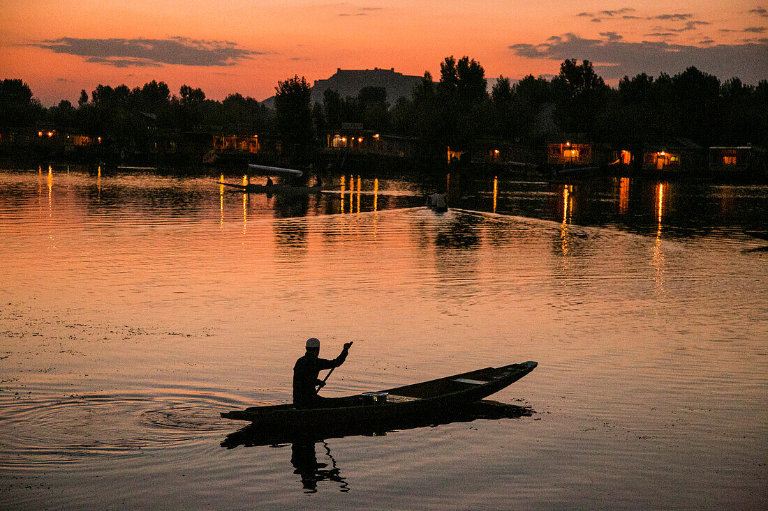 Mann auf einem Boot auf dem Dal-See in Srinagar bei Sonnenuntergang