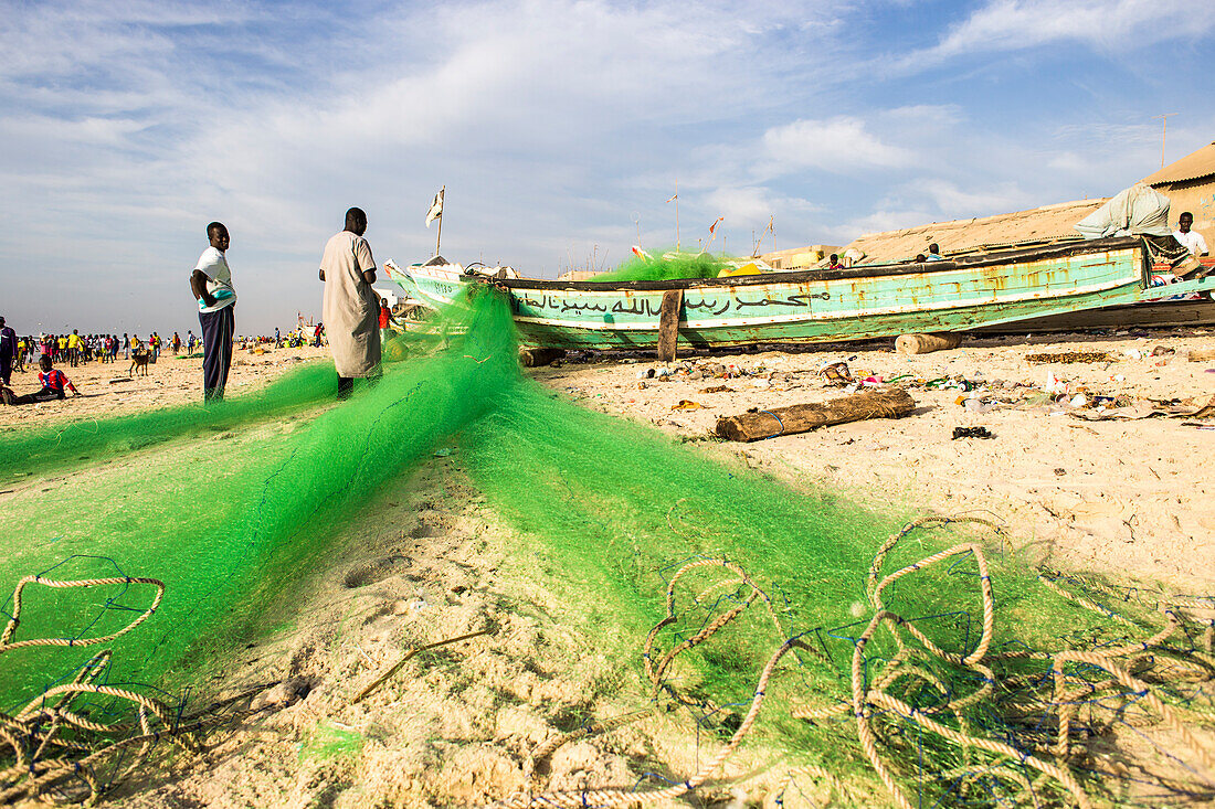 Männer reparieren Fischernetze am Strand von Saint-Louis