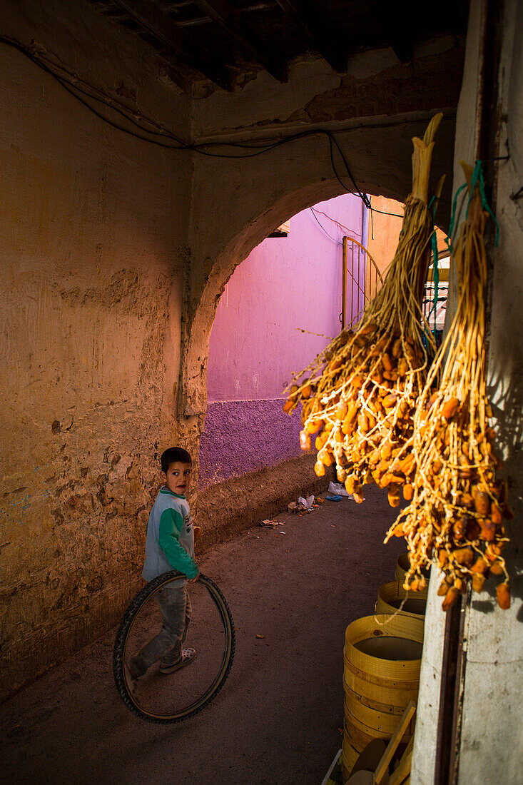 Boy plays with a wheel in Midelt's bazaar