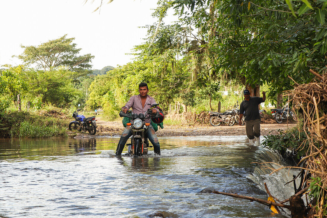 Mann überquert Fluss auf Motorrad, Matagalpa, Nicaragua