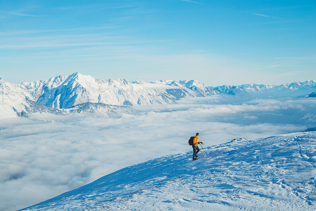 A mountaineer snowshoeing on the Patscherkofel mountain with the fog-covered Inn Valley in the background, Patscherkofel, Innsbruck Land, Tyrol, Austria, Europe