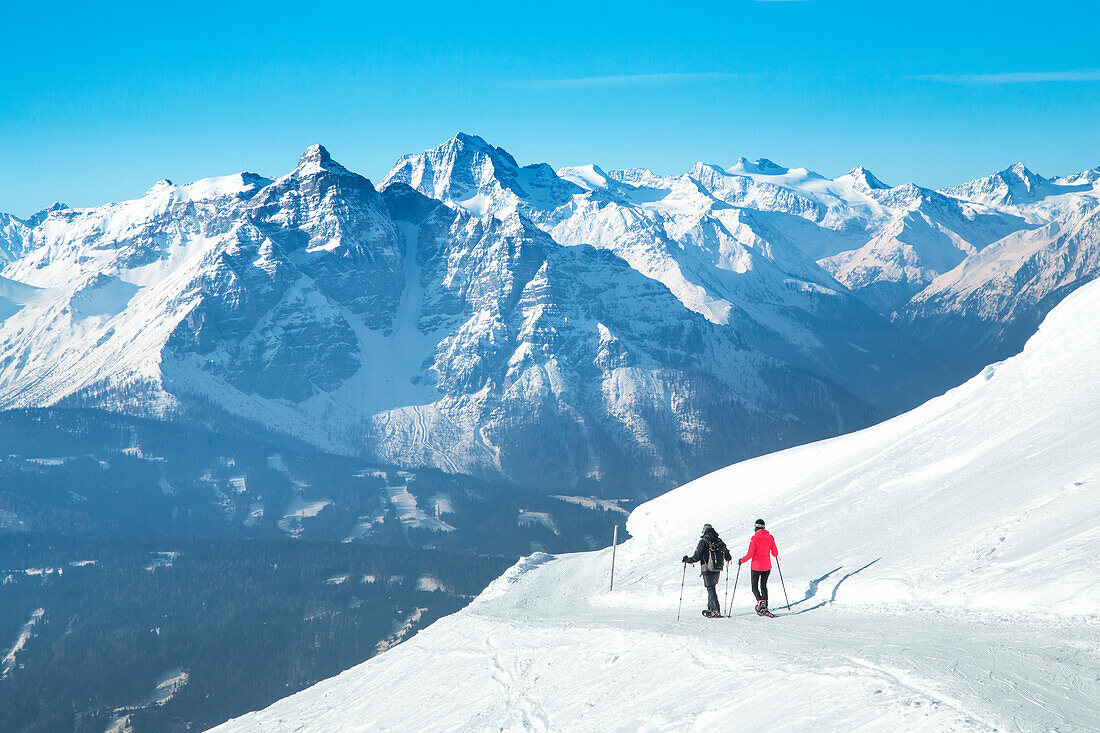 Ein Bergsteigerpaar beim Schneeschuhwandern mit den Stubaier Gipfeln im Hintergrund, Patscherkofel, Innsbruck Land, Tirol, Österreich, Europa