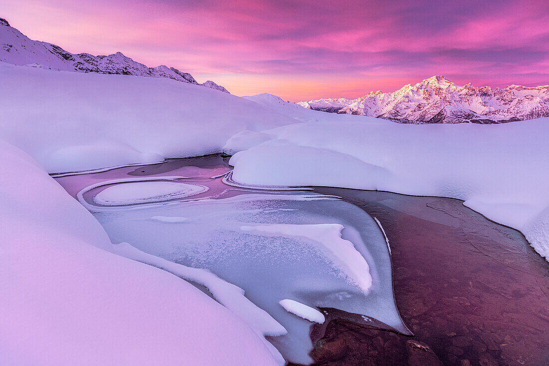 Verrückte Form in einem gefrorenen Alpensee bei Sonnenaufgang mit Blick auf den Monte Disgrazia. Valmalenco, Valtellina, Lombardei, Italien, Europa