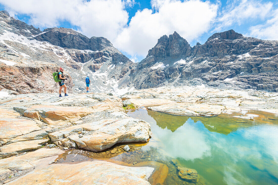 Hikers at Gran Lac de Tzere, Vallone delle Cime Bianche, Val d Ayas, Italian alps, Aosta valley, Italy