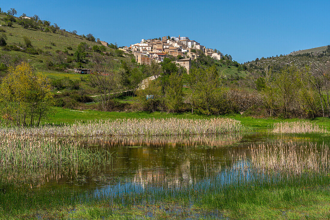 Das kleine Bergdorf San Benedetto in Perillis. Im Vordergrund ein Teich in der Talsohle mit Schilf und Weiden. Abruzzen, Italien