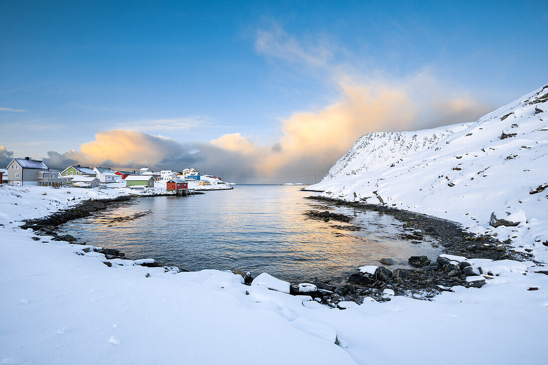 Das Küstendorf Sorvaer ist während des Sonnenaufgangs im kalten arktischen Winter mit Schnee bedeckt (Insel Soroya, Hasvik, Troms og Finnmark, Norwegen)