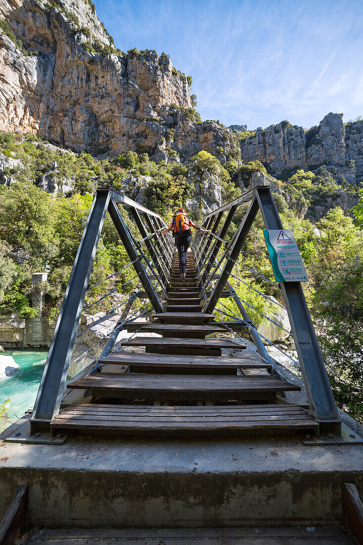 A female hiker is crossing the Verdon river on the Passerelle de l'Estellié in the Verdon Gorge (Var department, Provence-Alpes-Côte d'Azur, France, Europe) (MR)