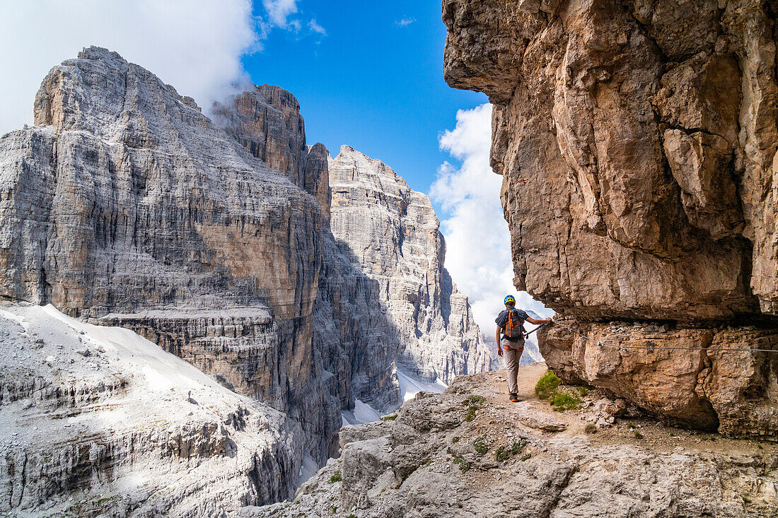 Ein Wanderer auf dem Eisenweg des Bocchette centrali-Höhenwegs, mit dem Berg Tosa im Hintergrund. Madonna di Campiglio, Trentino, Italien.