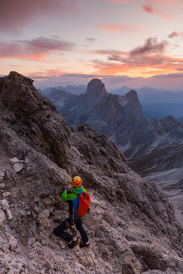 Hiker along the iron path to Catinaccio di Antermoia mount from Principe refuge atu sunset. Pozza di Fassa, Fassa Valley, Trentino, Italy.