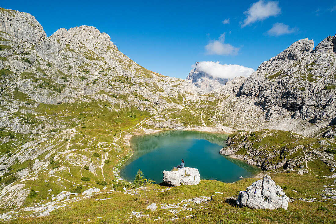 Ein Wanderer bewundert den Coldai Alpinsee an einem sonnigen Sommertag. Alleghe, Belluno, Venetien, Italien.