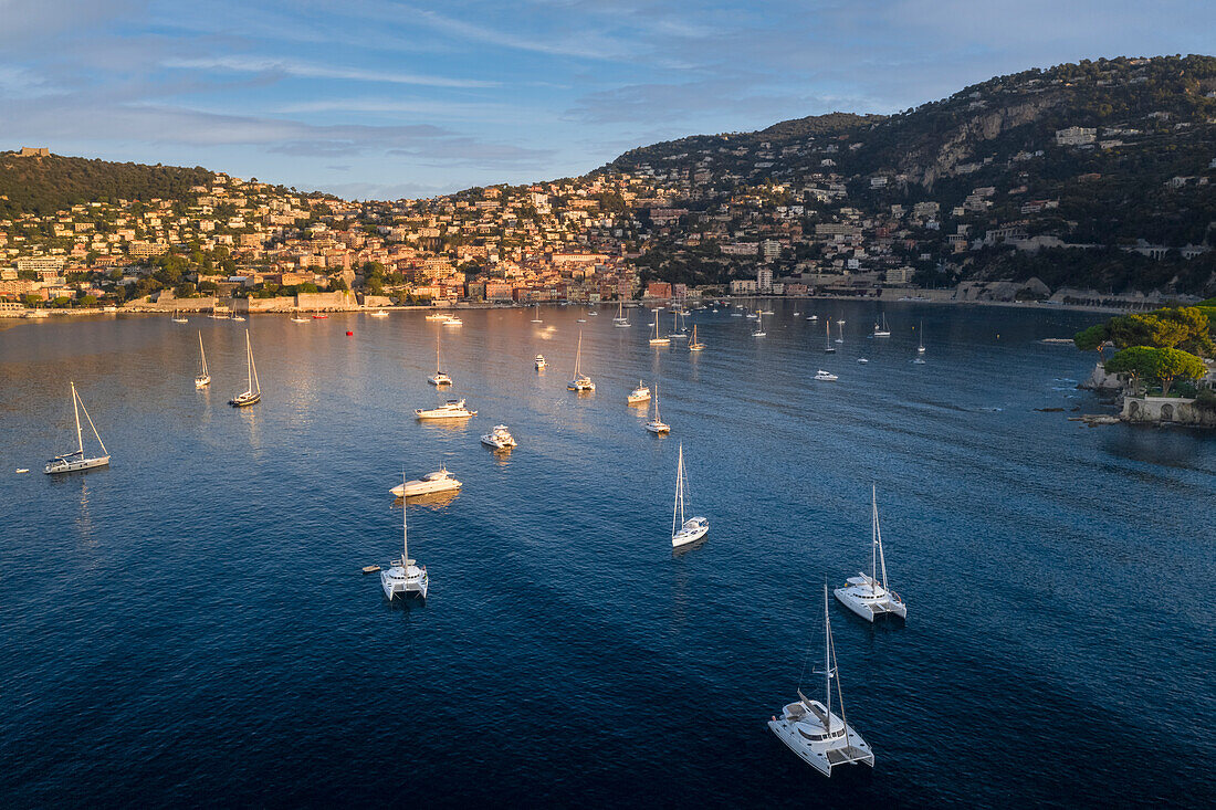 Sailing boats moored in the bay in front of Villefranche village at sunrise (Villefranche-sur-Mer, Beausoleil canton, Nice, Alpes-Maritimes department, Provence-Alpes-Cote d'Azur region, France, Europe)