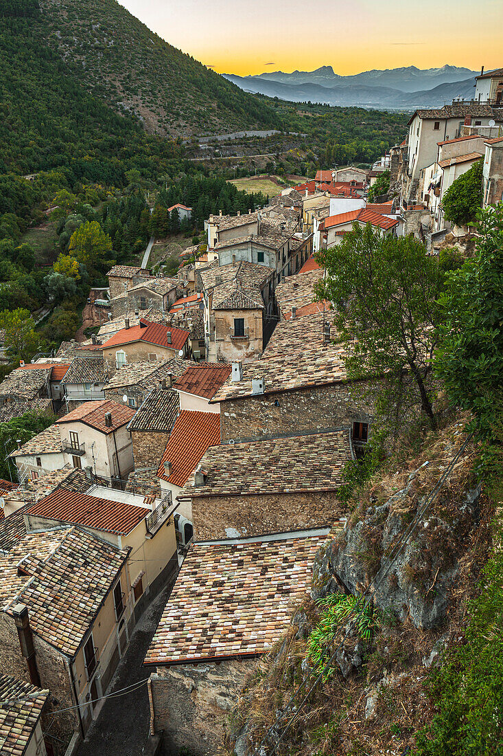 Panorama of a medieval village seen from above with the houses leaning against each other. In the background, the Gran Sasso chain at sunset. Pettorano sul Gizio, province of L'Aquila, Abruzzo, Italy, Europe