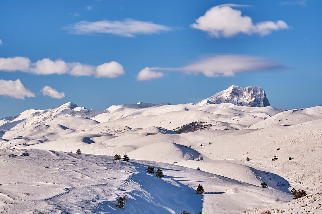 Corno Grande peak under a lenticular cloud and high hills covered of snow, Gran Sasso National Park. Abruzzo, Italy.