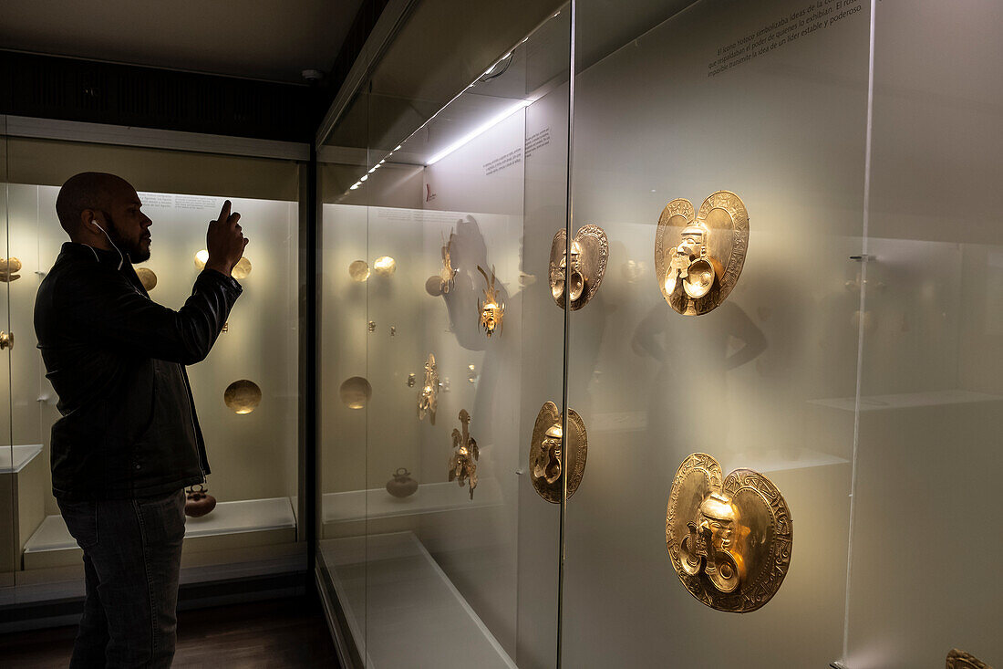 Visitor observing Pectorals, Pre-Columbian goldwork collection, Gold museum, Museo del Oro, Bogota, Colombia, America