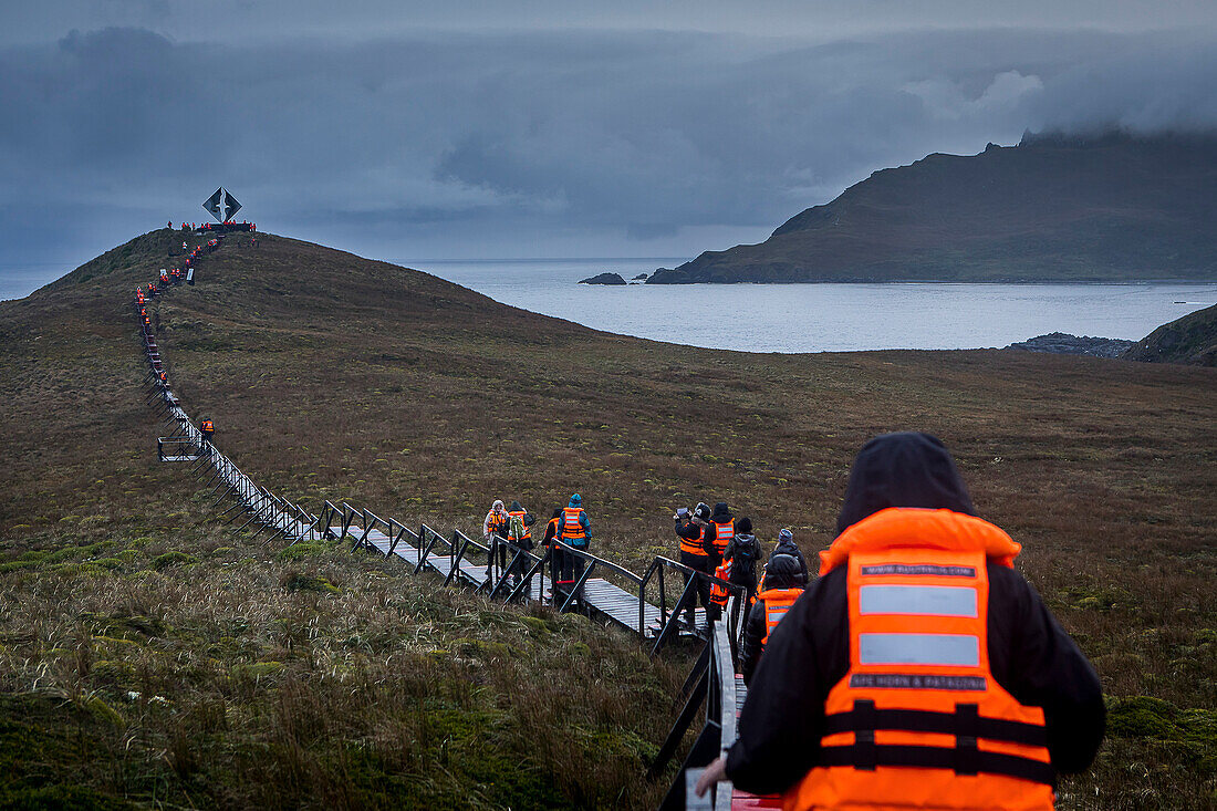 Explorers walking to Albatross memorial for lost mariners, Cape Horn, Tierra de Fuego, Patagonia, Chile