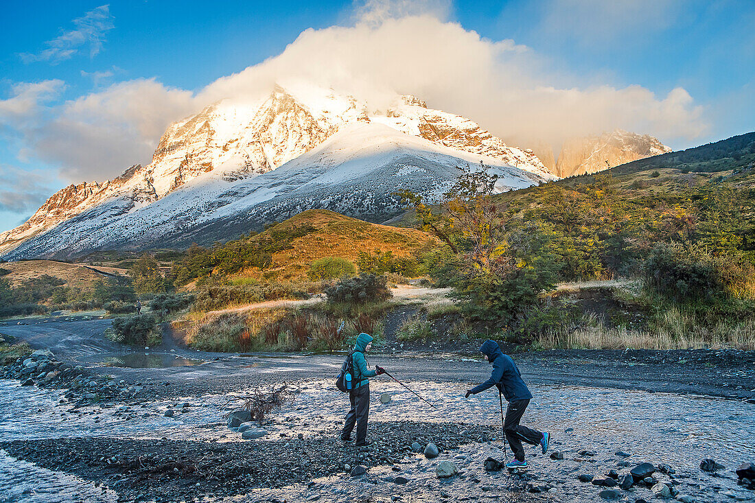 Wanderer überqueren einen Fluss und wandern zwischen der Torres-Hütte und der Cuernos-Hütte, Torres del Paine Nationalpark, Patagonien, Chile