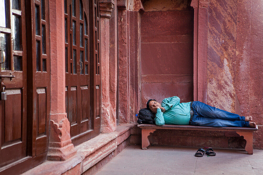 Erschöpfter Tourist. Schlafender Besucher im Haupttor des Agra Forts, UNESCO-Weltkulturerbe, Agra, Indien