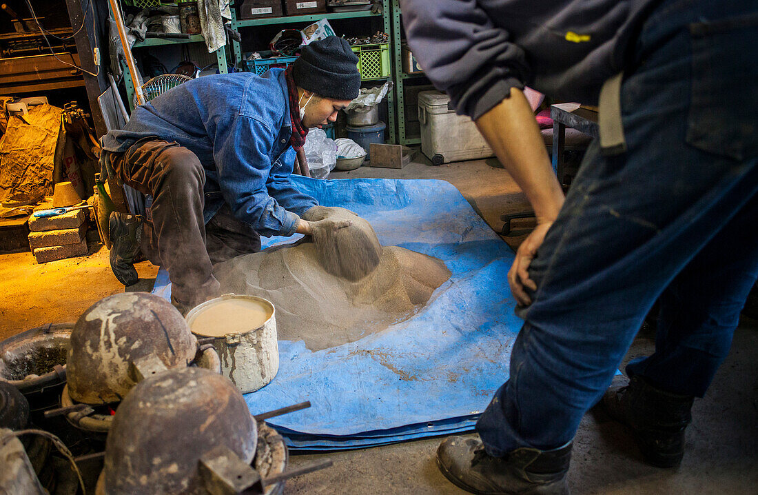 Sie prüfen die Qualität des Sandes für die Herstellung von Schlamm und bauen eine Form für die Herstellung einer eisernen Teekanne oder Tetsubin, nanbu tekki, Werkstatt der Familie Koizumi, Morioka, Präfektur Iwate, Japan