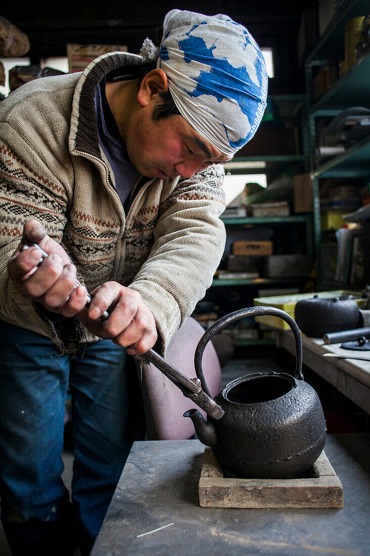 Takahiro Koizumi legt den Henkel an eine eiserne Teekanne oder Tetsubin, nanbu tekki, Werkstatt der Familie Koizumi, Handwerker seit 1659, Morioka, Präfektur Iwate, Japan