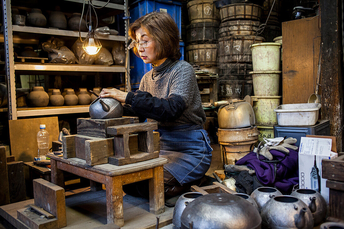 Morihisa Suzuki is putting the finishing touches at iron teapot or tetsubin, the only woman who has made teapots in the nearly 400 years of history that has molten iron crafts in Iwate, in Workshop of Morihisha Suzuki,craftsmen since 1625, nanbu tekki, Morioka, Iwate Prefecture, Japan