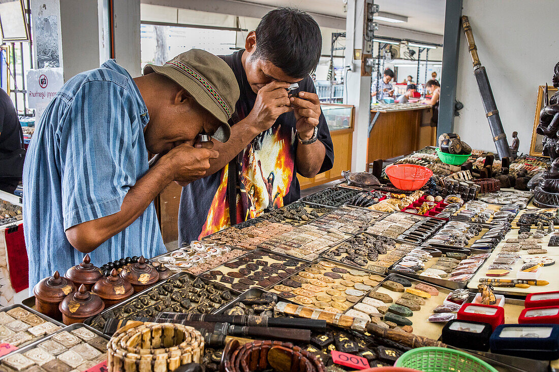 Sammler mit Vergrößerungsglas suchen kleine buddhistische Amulette, Amulettmarkt, Bangkok, Thailand, Asien