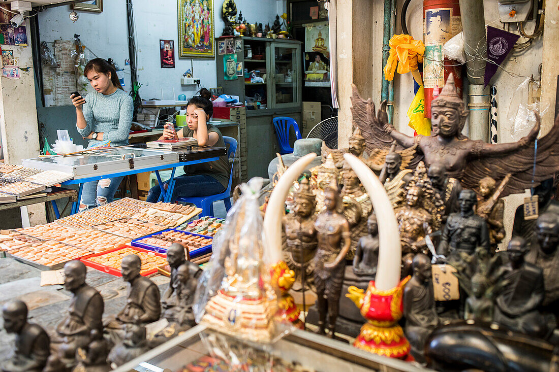 Verkäufer beobachten das Telefon, auf dem Amulettmarkt, Bangkok, Thailand
