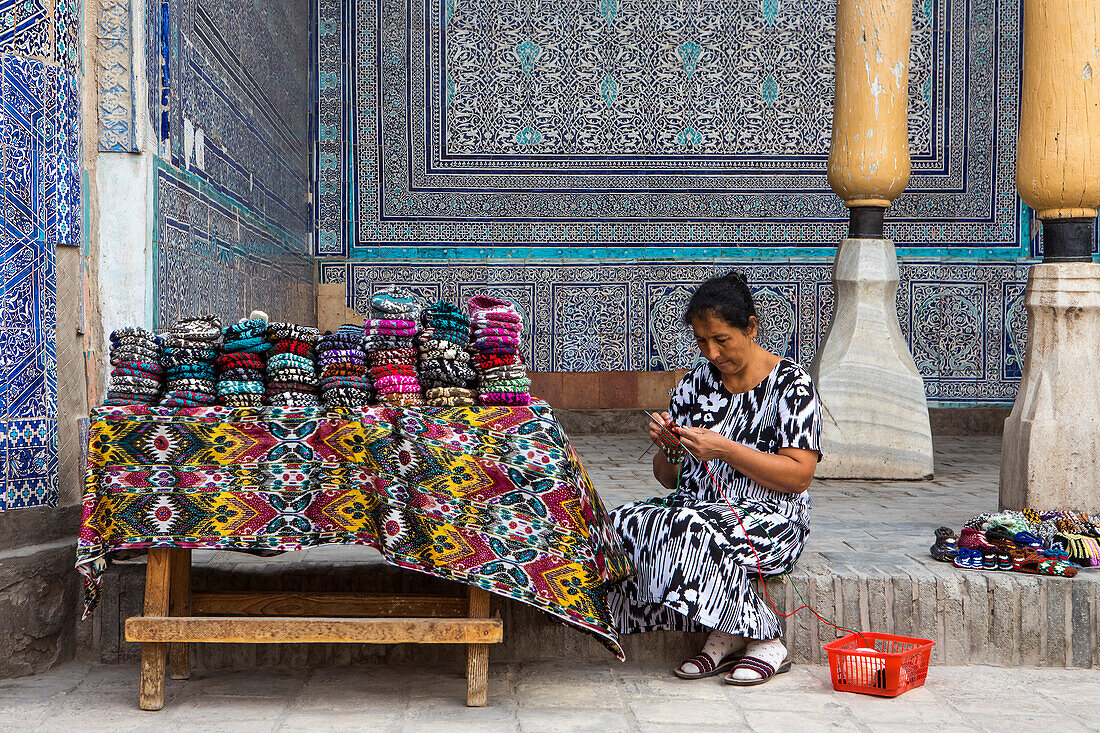 Wächterin, die auch von ihr hergestellte Strickwaren verkauft, in der Sommermoschee, innerhalb der Arche Kuhna, Chiwa, Usbekistan