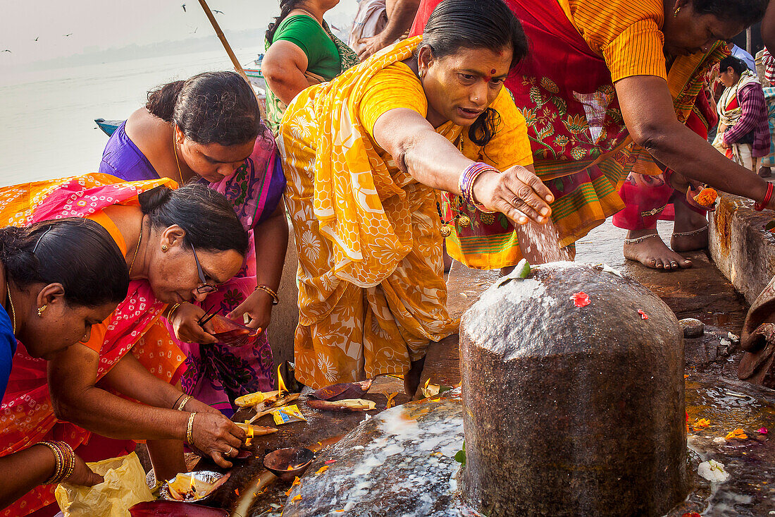 Pilgrims making a ritual offering, and praying, ghats in Ganges river, Varanasi, Uttar Pradesh, India.