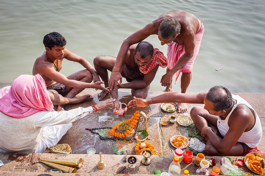 Pilgrims making a ritual offering and praying, ghats of Ganges river, Varanasi, Uttar Pradesh, India.