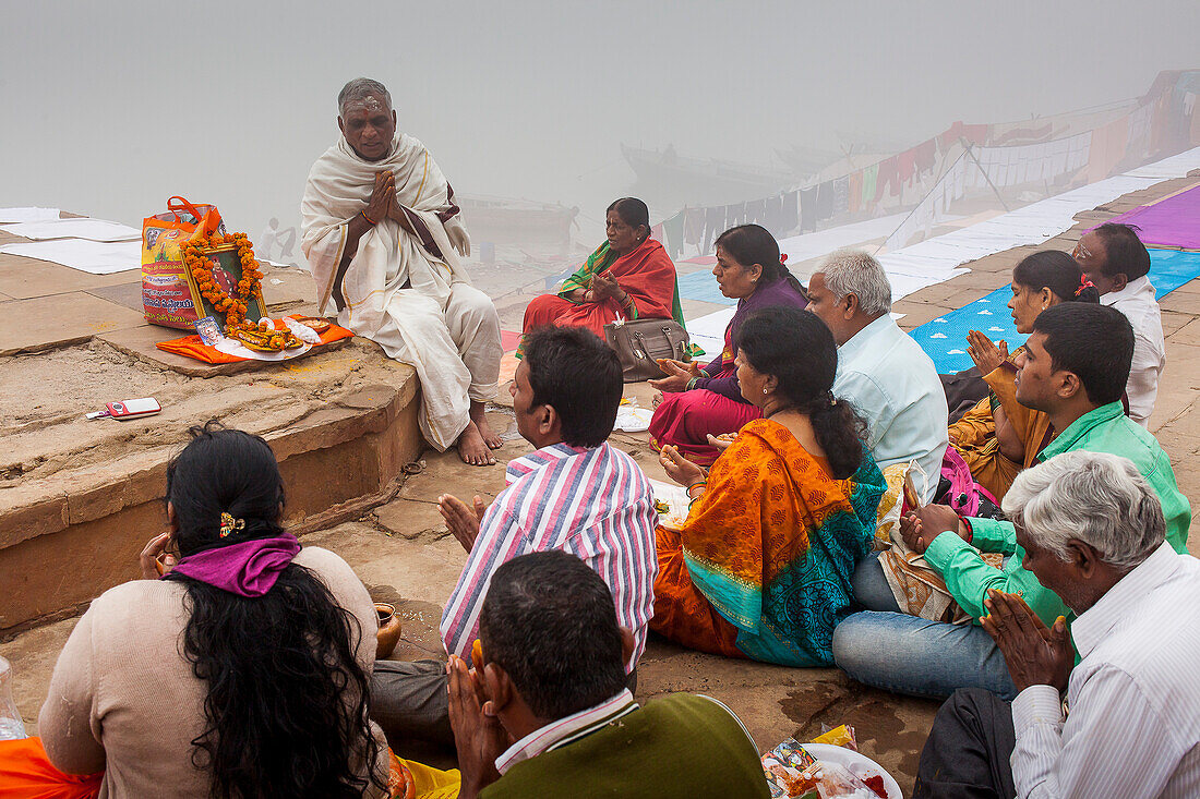 Pilgrims making a ritual offering and praying, ghats of Ganges river, Varanasi, Uttar Pradesh, India.