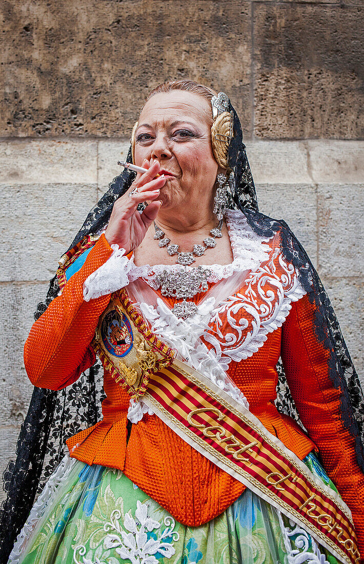 Rauchende Frau im Fallera-Kostüm während des Blumenkorsos zu Ehren der "Virgen de los desamparados", Fallas-Festival, Plaza de la Virgen, Valencia