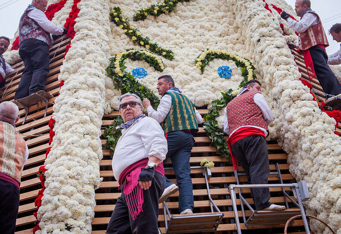 Männer legen Blumenopfer auf die große hölzerne Statue der Virgen de los Desamparados, Fallas-Fest, Plaza de la Virgen, Valencia