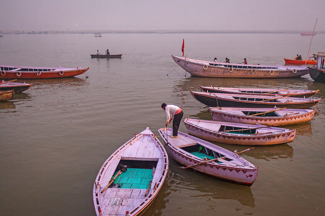 Fisherman, in background boats of tourists, in Ganges river, Varanasi, Uttar Pradesh, India.