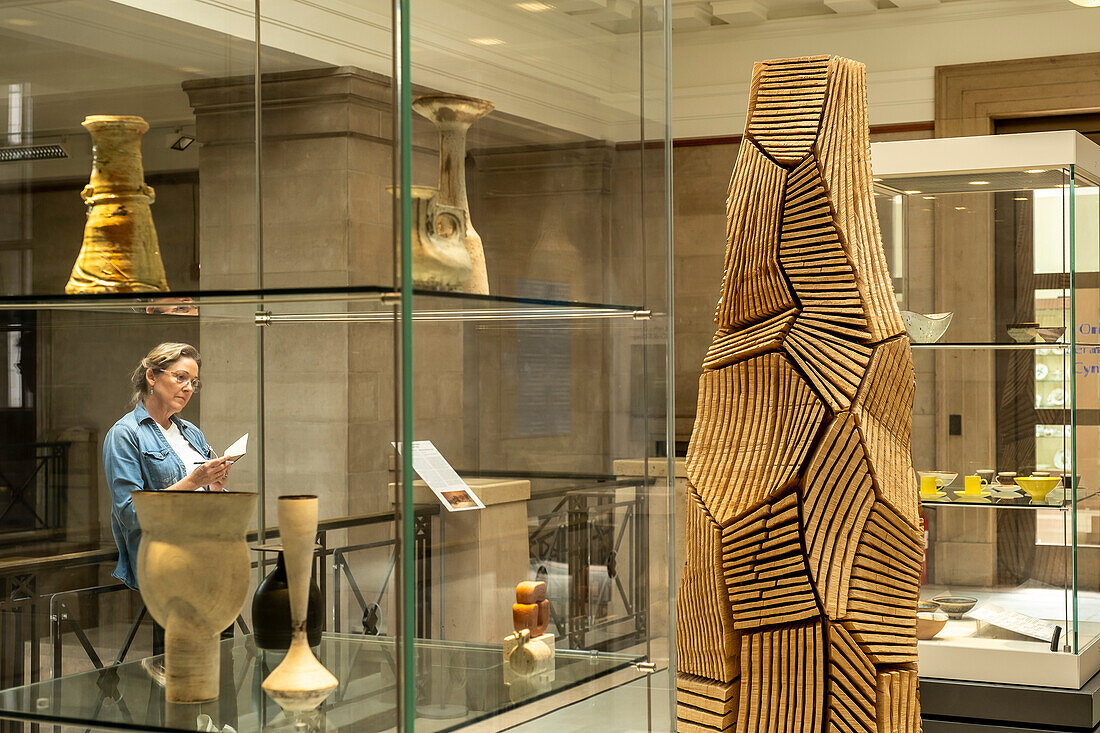 Frau bei der Betrachtung der mehrteiligen Säulenskulptur von David Nash, National Museum of Wales, Cardiff, Wales