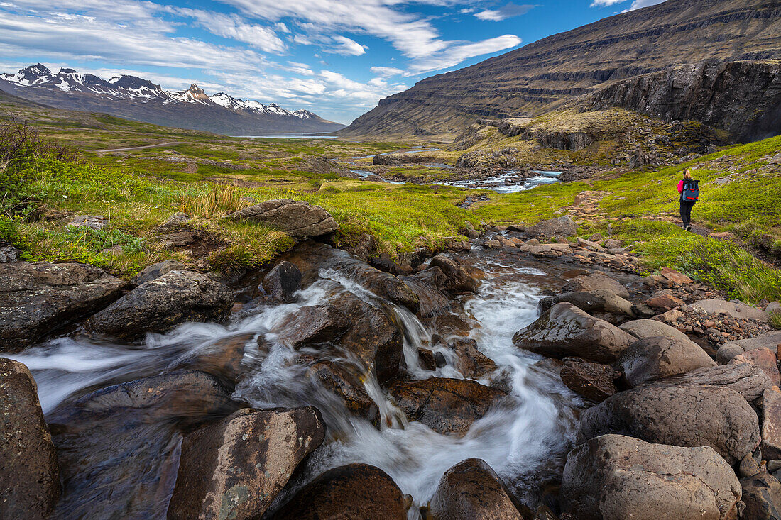 Person walks around Folaldafoss waterfall and Berufjordur during summer, Austurland, Iceland, Northern Europe