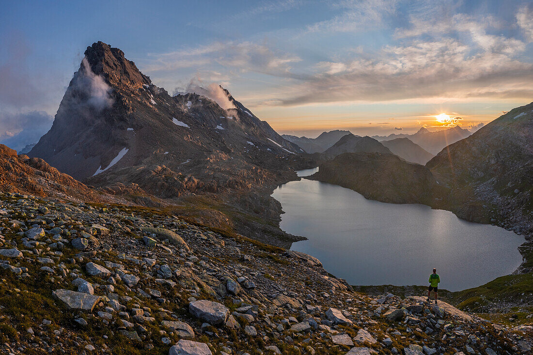 Luftaufnahme eines Mannes am Rossapass und Geisspfadsee bei Sonnenuntergang im Sommer, Alpe Devero, Val D'Ossola, Verbano Cusio Ossola, Piemont, Italien, Westeuropa