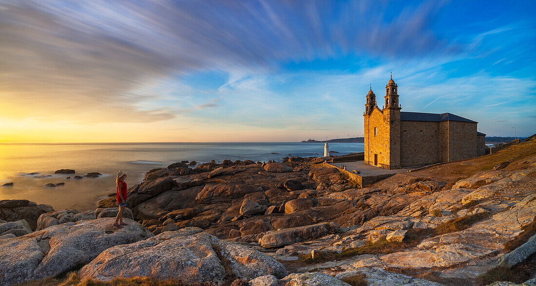 A woman observes Virxe da Barca Sanctuary at sunset during summer, Muxia, A Coruna, Galicia, Spain, Iberian Pensinsula, Western Europe