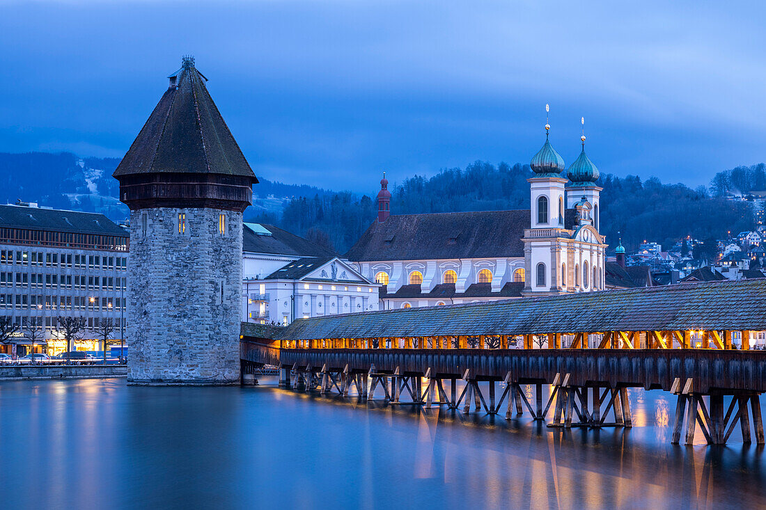 View of the Kapellbrücke bridge, the Jesuit Church and the Wasserturm at blue hour reflected on the Reuss river. Lucerne, canton of Lucerne, Switzerland.