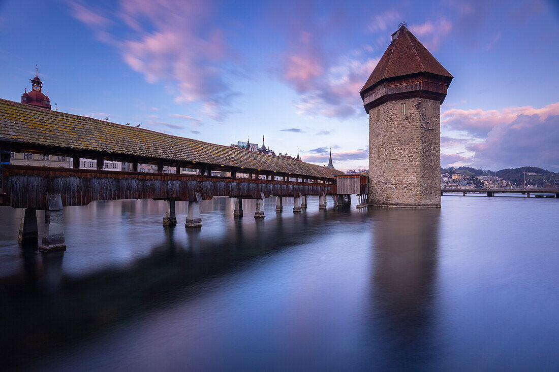 Blick auf die Kapellbrücke und den Wasserturm bei Sonnenuntergang mit Spiegelung in der Reuss. Luzern, Kanton Luzern, Schweiz.