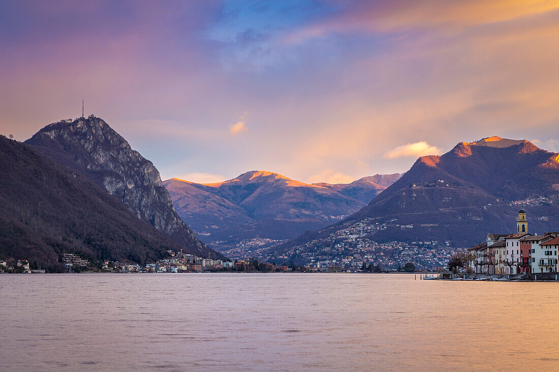 Sonnenaufgang in Brusino Arsizio und Lugano in der Ferne, Ceresio-See, Kanton Tessin, Schweiz.