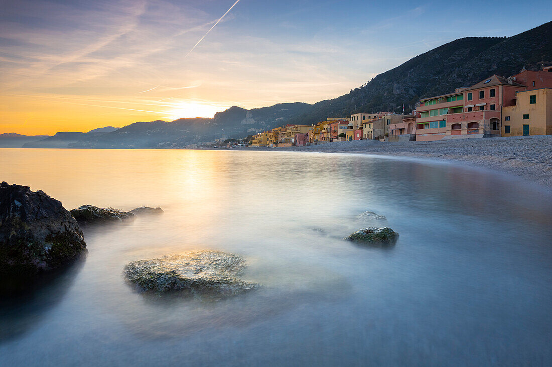Nebliger Sonnenuntergang über den bunten Häusern und dem Strand von Varigotti, Finale Ligure, Bezirk Savona, Ponente Riviera, Ligurien, Italien.