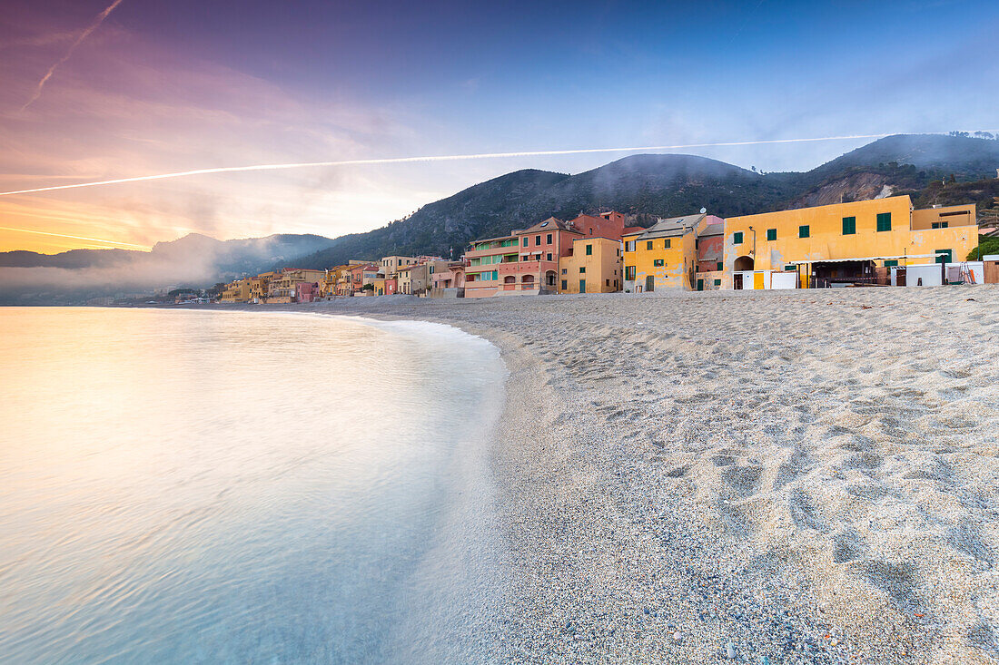 Nebliger Sonnenuntergang über den bunten Häusern und dem Strand von Varigotti, Finale Ligure, Bezirk Savona, Ponente Riviera, Ligurien, Italien.