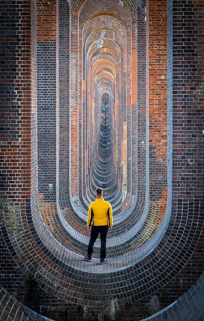 Eine Person starrt auf das Ouse-Tal-Viadukt aus dem darunter liegenden Gewölbe. Sussex, Südengland, Vereinigtes Königreich.