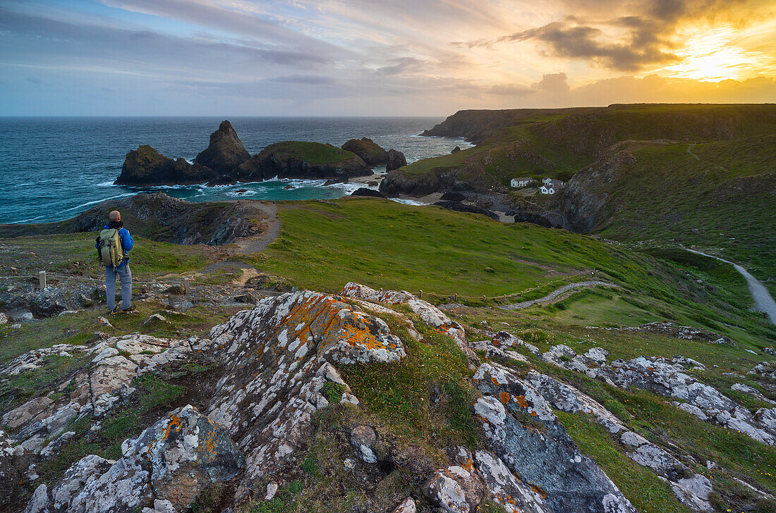 Ein Tourist in der Bucht von Kynance Cove mit ihren Stacks bei Sonnenuntergang, Lizard Peninsula, Cornwall, Vereinigtes Königreich, Nordeuropa